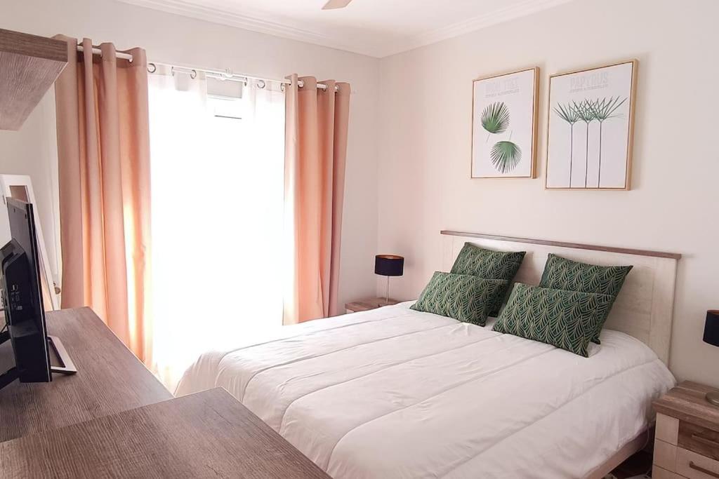 a bedroom with a large white bed with green pillows at Casa de Praia da Zezinha in Costa da Caparica