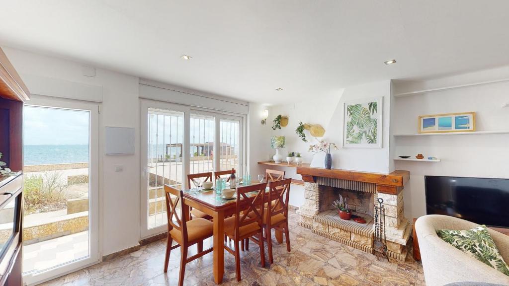 ein Wohnzimmer mit Tisch und Stühlen und einem Kamin in der Unterkunft Casa de Lago - A Murcia Holiday Rentals Property in Playa de los Nietos