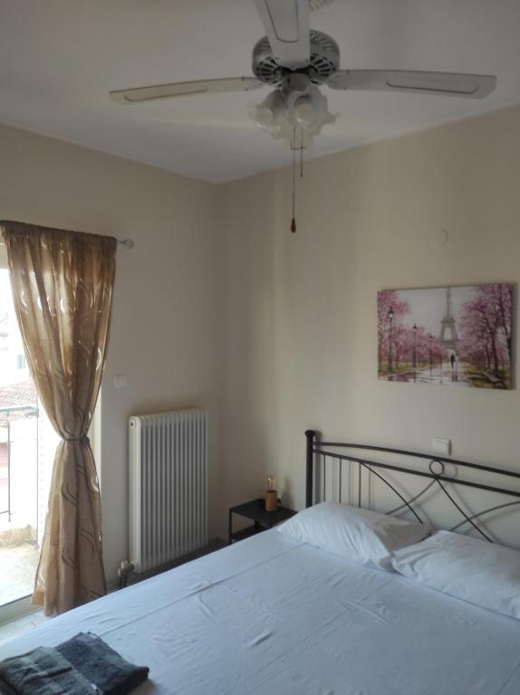 um quarto com uma cama, uma ventoinha de tecto e uma janela em Nikos Apartments em Amarinthos
