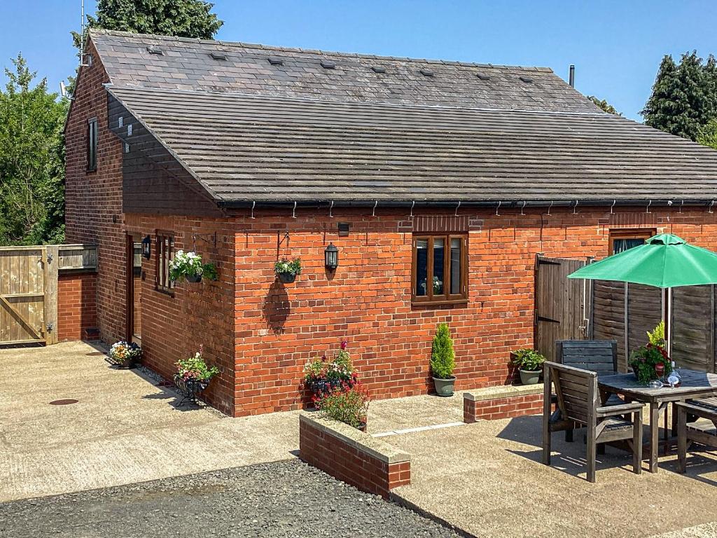 a brick house with a table and an umbrella at Nuthatch - 29363 in Ifton Heath
