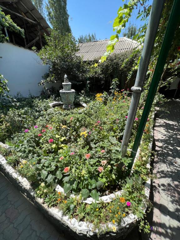 un jardín con flores y una fuente en un patio en Lovely home for you, en Osh
