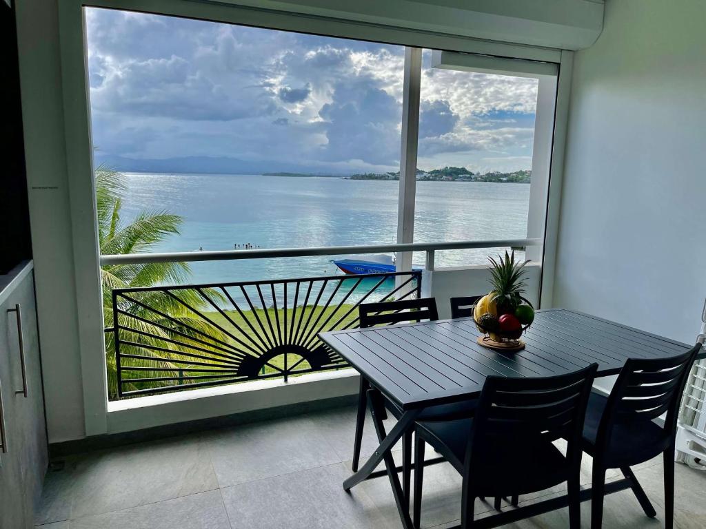 Karaibes Residence في لو جوسيير: طاولة وكراسي على شرفة مطلة على المحيط