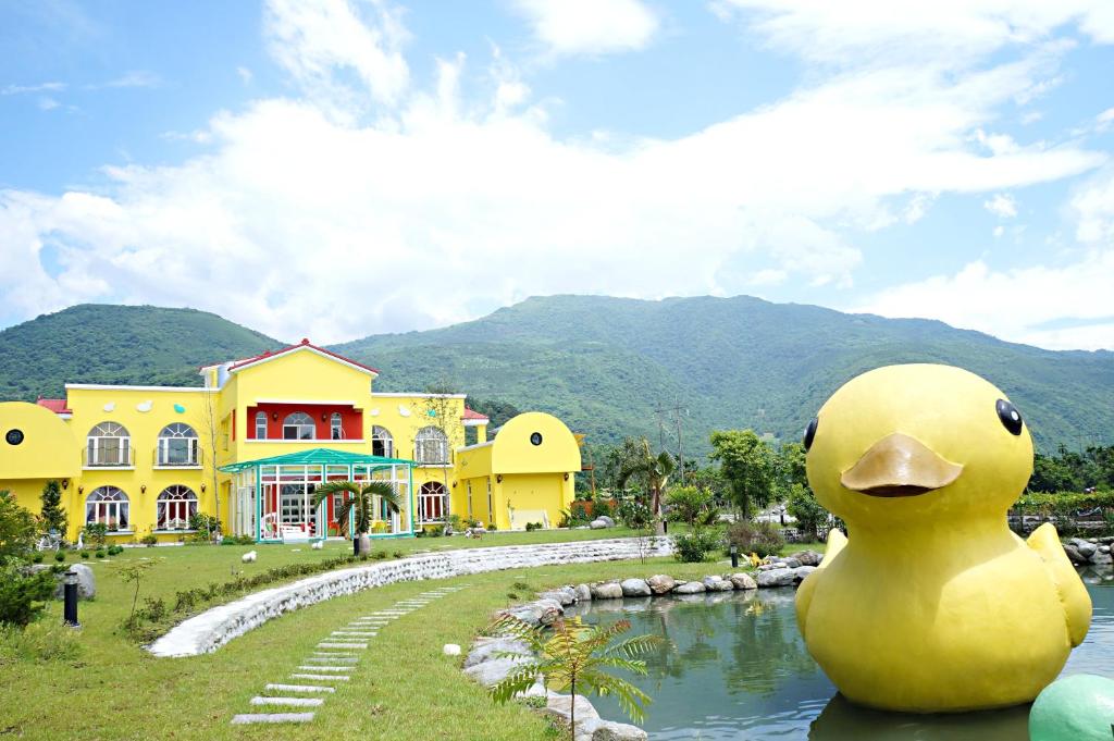 un gran edificio amarillo con un pato gigante de goma delante de él en 依比鴨鴨水岸會館 Ducking House, en Ruisui