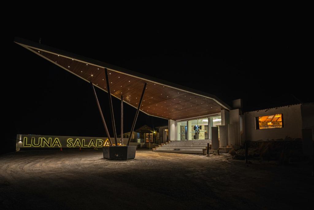 ein nachts beleuchtetes Gebäude mit einem beleuchteten Schild in der Unterkunft Hotel de Sal Luna Salada in Colchani
