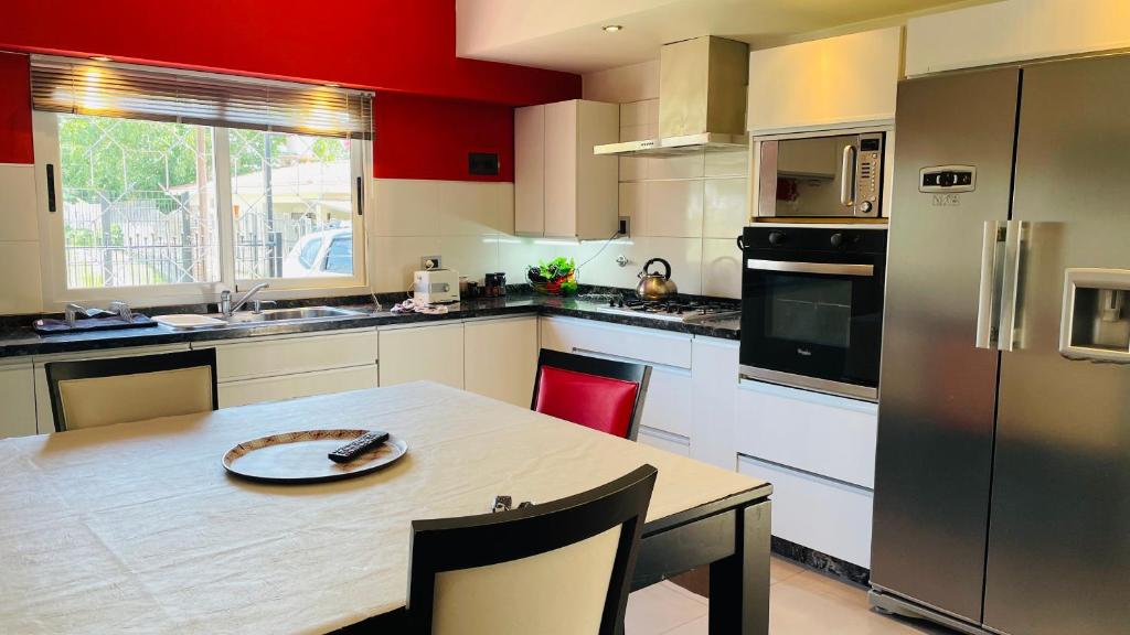cocina con mesa y cocina con paredes rojas en Excelente Casa c/ Pileta Cerca del Centro en Villa Carlos Paz