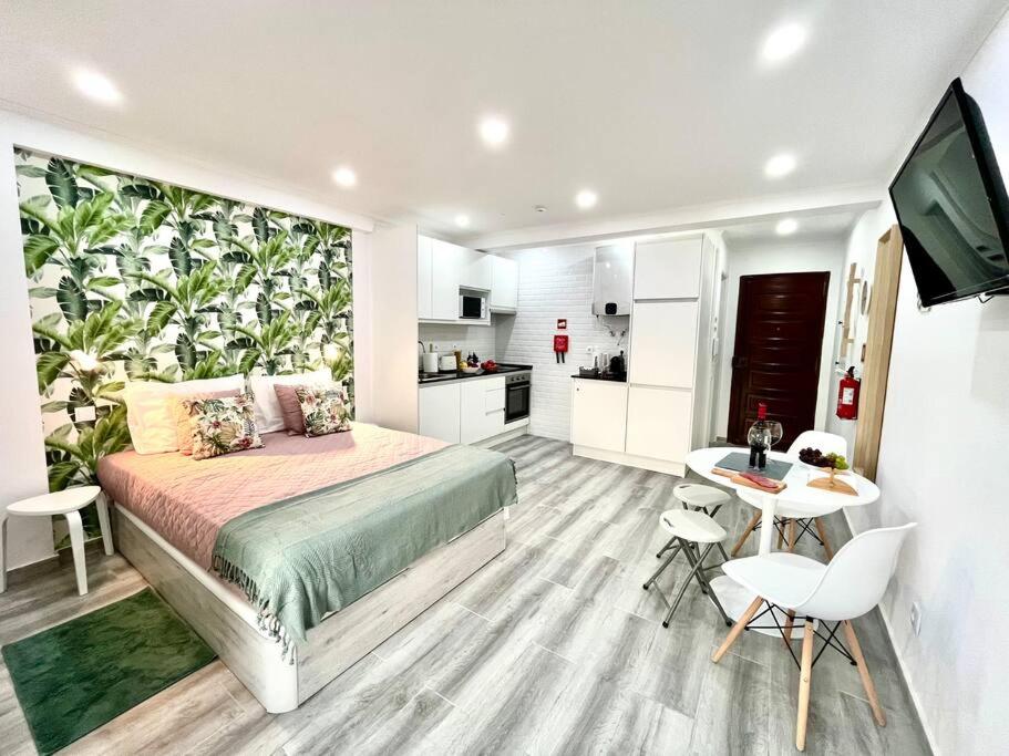 een slaapkamer met een bed en een tafel en een keuken bij New-Romantic studio near the beach! in Paço de Arcos