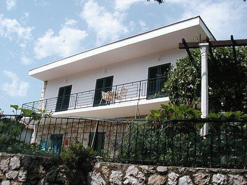 a white house with a dog sitting on the balcony at Rooms Sentic in Dubrovnik