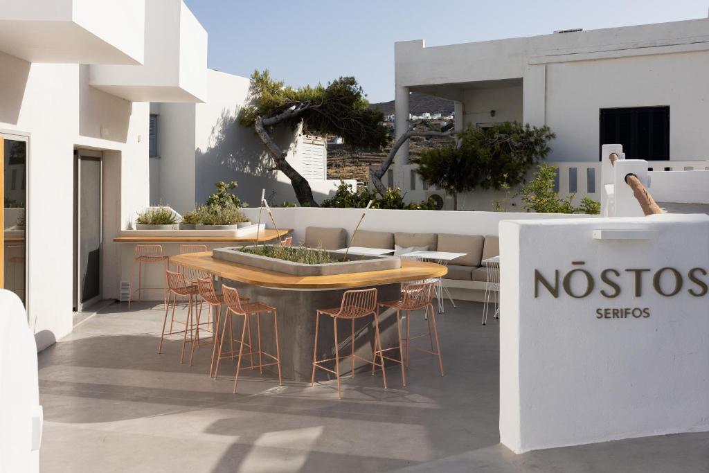 a table and chairs on a patio with a sign at NŌSTOS Serifos in Livadi