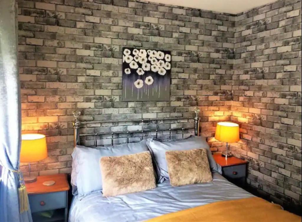 a bedroom with a brick wall with a bed and two lamps at Springer Villa, 2 bed, Newquay in Newquay