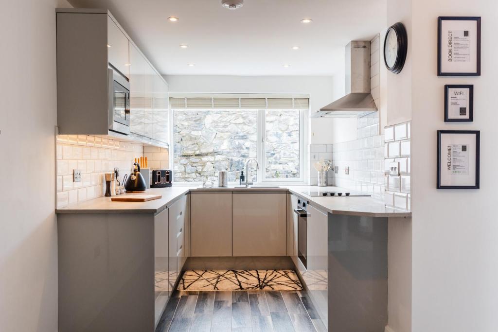 a kitchen with white cabinets and a large window at Luxury House in the Heart of Mumbles Village in The Mumbles