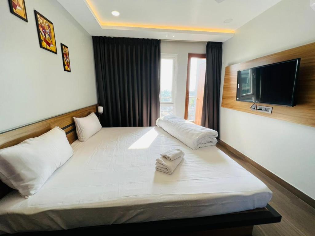 una camera d'albergo con un letto e una TV a parete di HOTEL ROYAL VANILLA a Siliguri