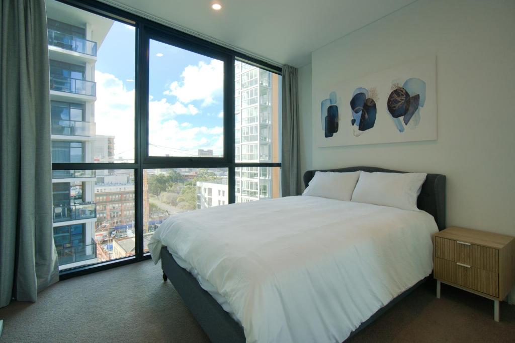 a bedroom with a large bed and large windows at Contemporary 3BR Paradise on Franklin Street in Adelaide