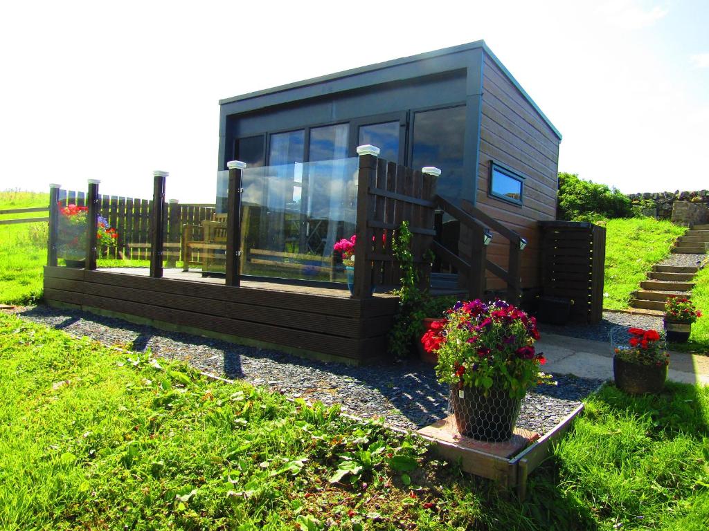 a tiny house sitting in a yard with flowers at Balvicar Beag in Oban