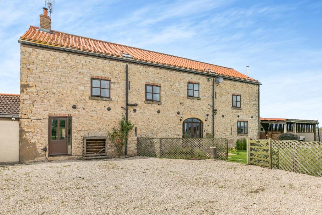 un vieux bâtiment en briques avec une clôture devant lui dans l'établissement Stubbs Grange Barn, à Fenwick