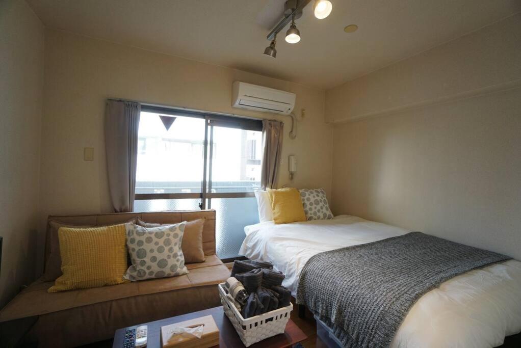 een kleine slaapkamer met een bed en een raam bij Apartment House Floor Assemble 402 in Osaka