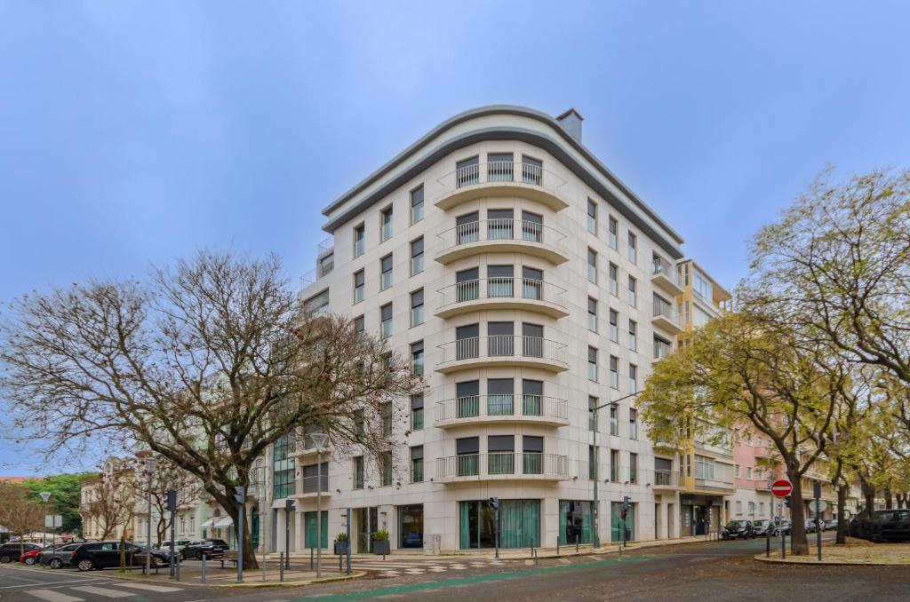 a white building on a city street with trees at Olissippo Saldanha in Lisbon