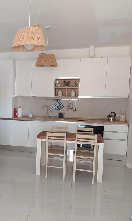 a kitchen with white cabinets and a table and chairs at LECCE AL MARE in San Cataldo