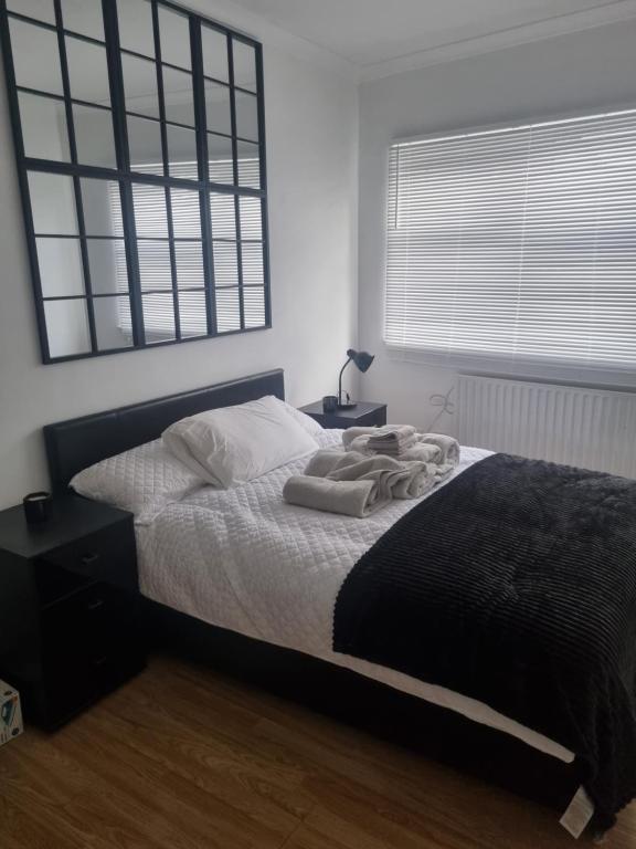 een slaapkamer met een bed met een zwarte deken en een raam bij Manhattan Studio flat northbridge services in Londen