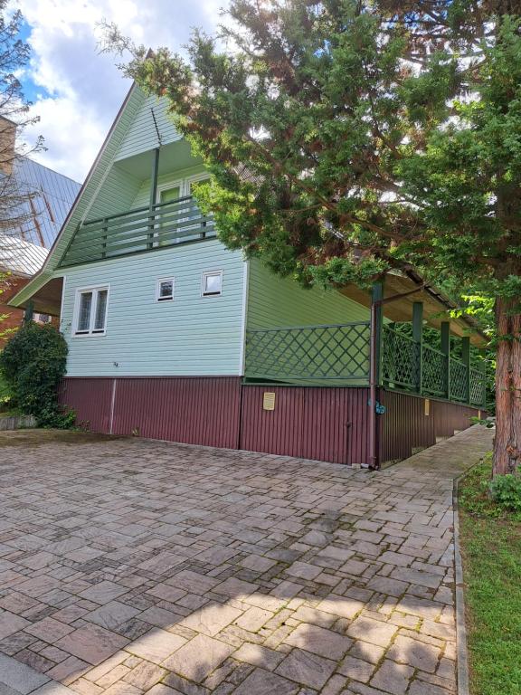 a green house with a red fence next to a driveway at Domek letniskowy Werlas Bieszczady in Werlas