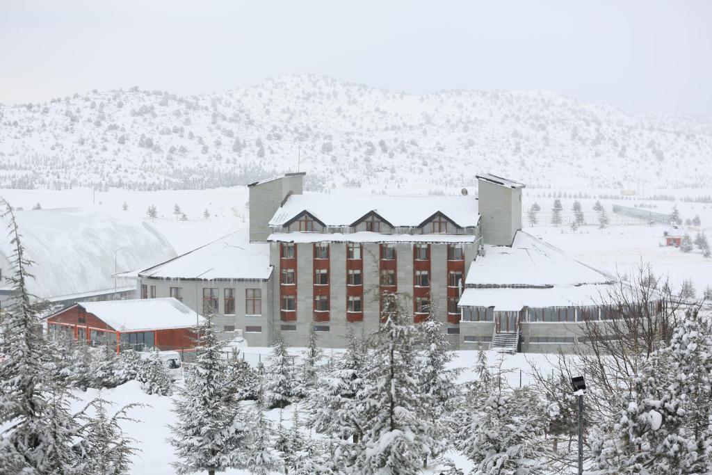 a building covered in snow with trees and mountains at West Davraz Hotel in Cobanisa