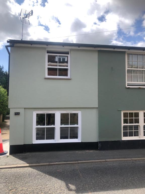 a white building with four windows on a street at Dinky cottage in Brightlingsea