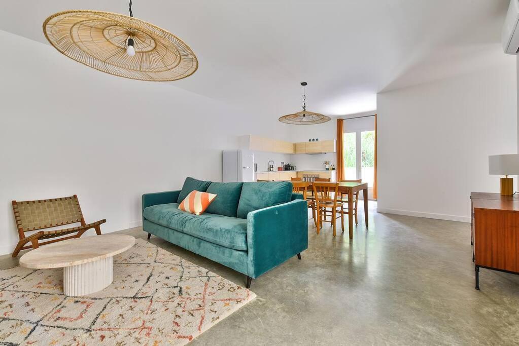 a living room with a blue couch and a table at NOCNOC Le Joïa - Petite piscine et jardin en ville in Montpellier