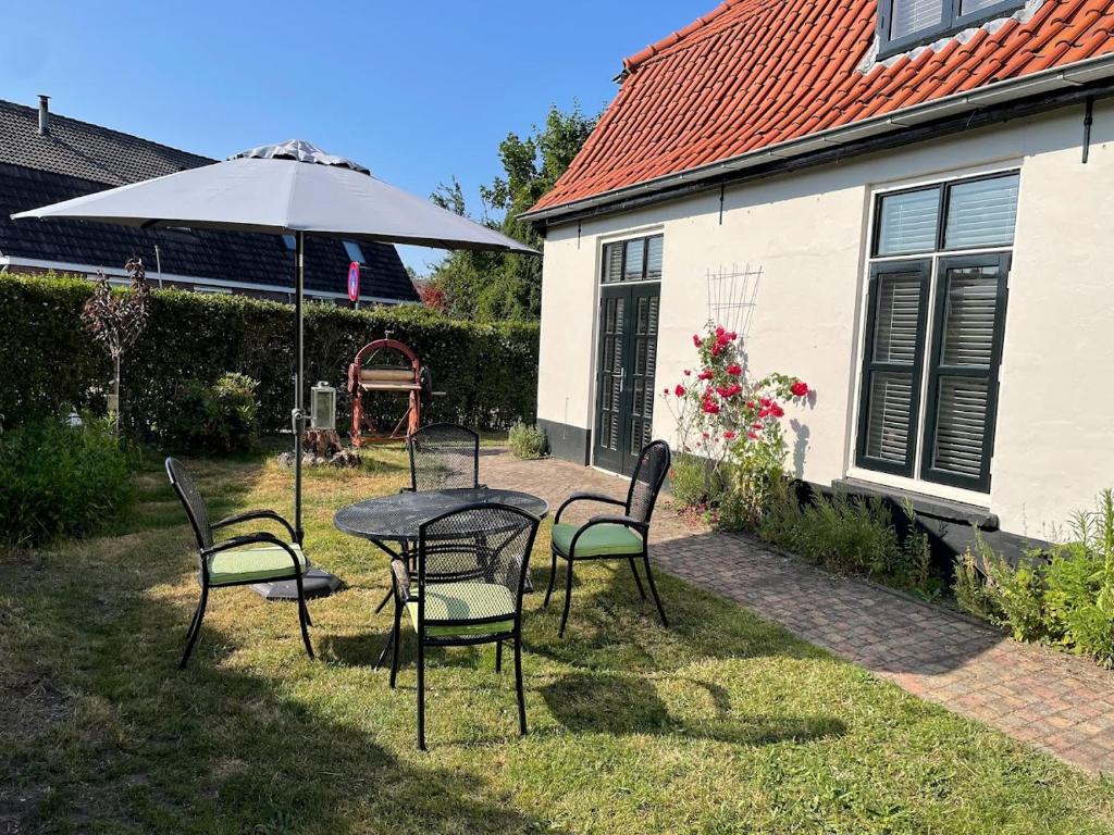 une terrasse avec une table, des chaises et un parasol dans l'établissement B&B Wasboerderij Beek Ubbergen, à Beek