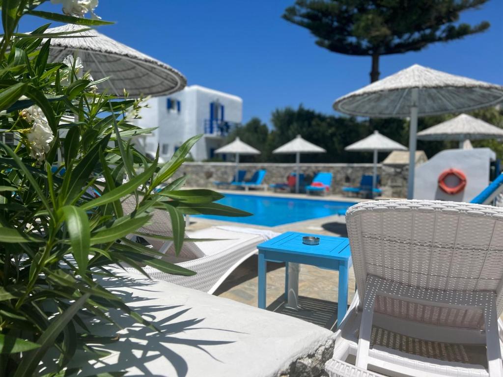 einen Tisch und Stühle neben einem Pool mit Sonnenschirmen in der Unterkunft Anemos Apartments in Ornos