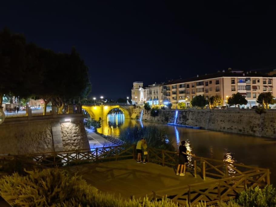 twee mensen die 's nachts op een brug over een rivier staan bij Panoche Apartamento a 750m de la Catedral A/A in Murcia