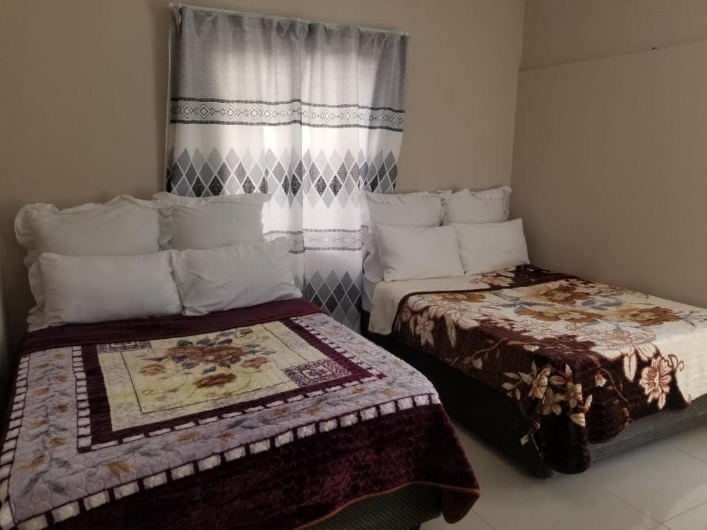 a small room with two beds and a window at Pinto City Motel in Kempton Park