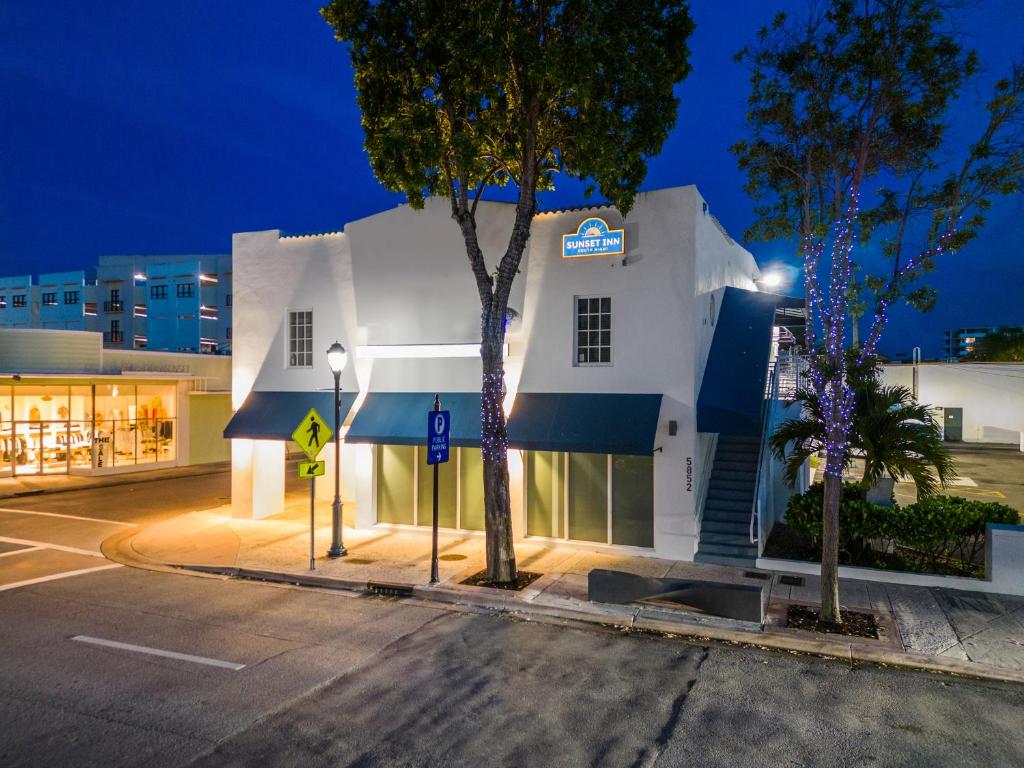 un bâtiment blanc avec des auvents bleus dans une rue dans l'établissement Sunset Inn-South Miami, à South Miami
