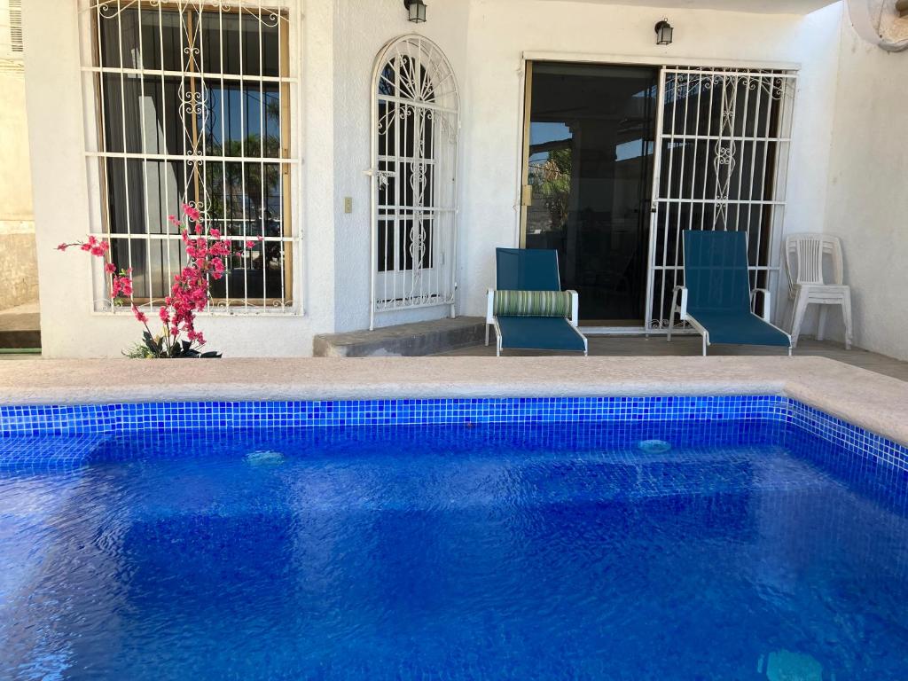 a blue swimming pool with two chairs and a house at Vista al mar y alberca privada en Sector Bahía in San Carlos