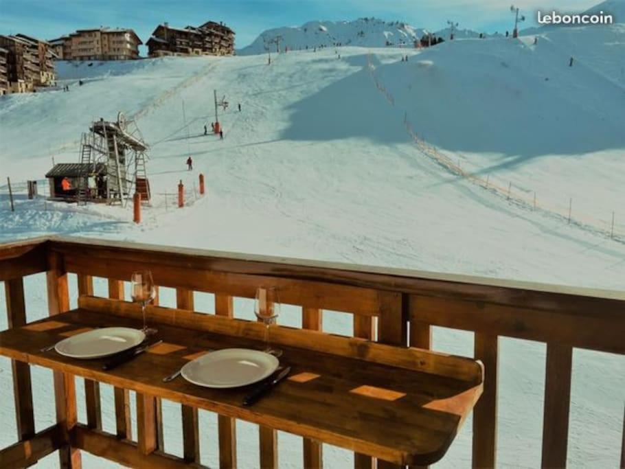 une table en bois avec des assiettes au sommet d'une piste de ski dans l'établissement Duplex plein sud_skis aux pieds_Plagne villages, à La Plagne Tarentaise