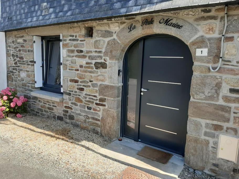 un edificio de piedra con una puerta de garaje negra en La Perle Marine, en Le Vivier-sur-Mer