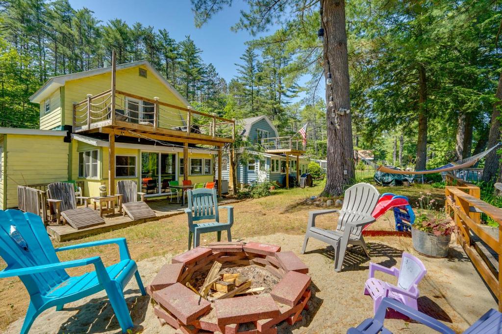 a backyard with chairs and a fire pit at Riverfront Hadley Getaway with Fire Pit and Boat Dock! in Lake Luzerne