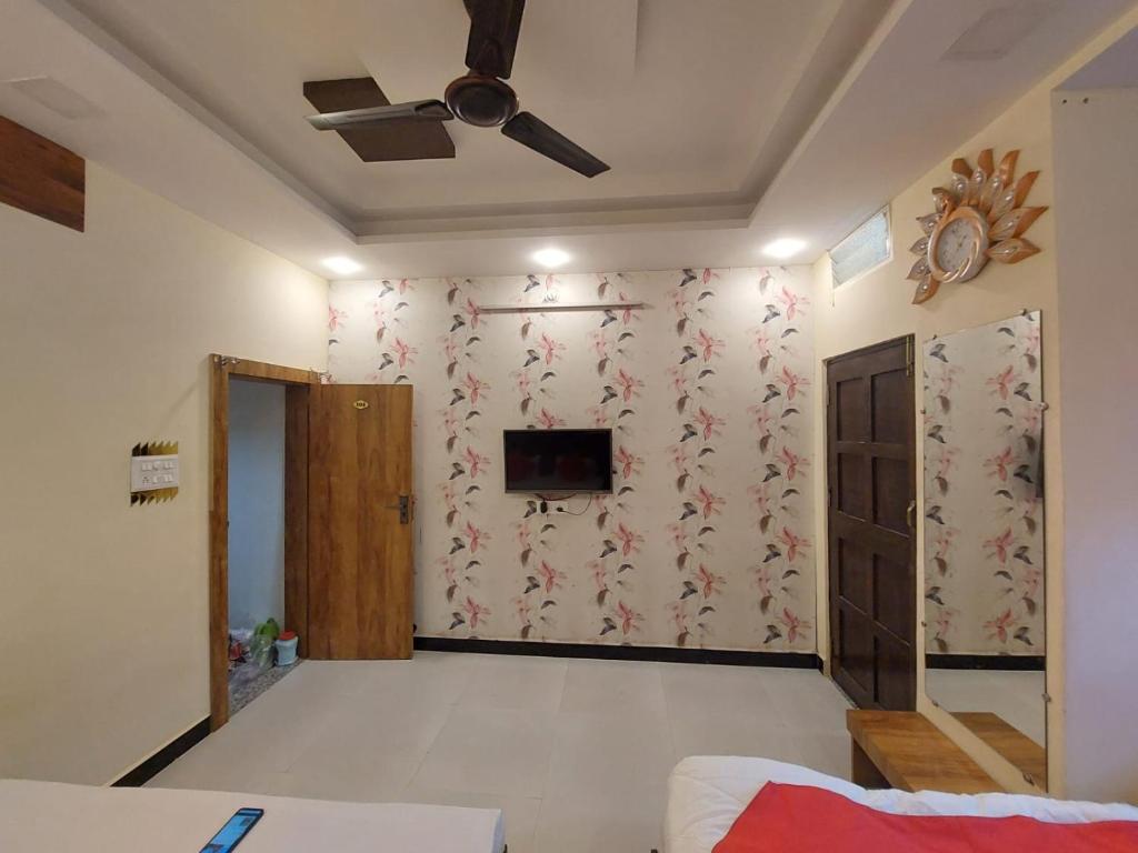 a living room with a ceiling fan and a tv at Parvati home stay in Ujjain