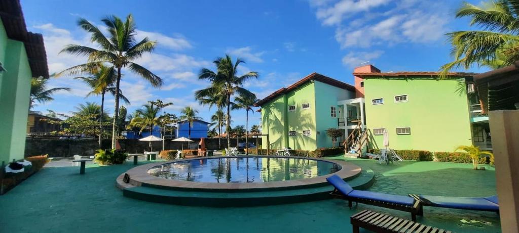 a resort with a swimming pool and palm trees at Apartamento Condomínio Taperapuan Vilage in Porto Seguro