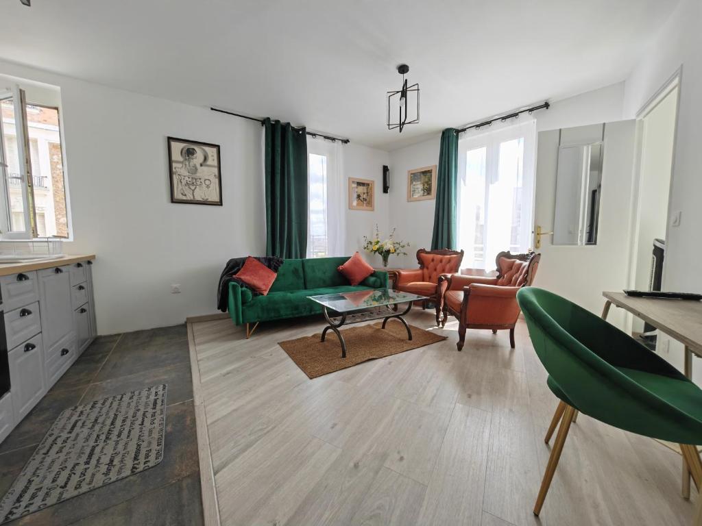 ein Wohnzimmer mit einem grünen Sofa und Stühlen in der Unterkunft Cosy Appartement T2 proche Paris in Ivry-sur-Seine