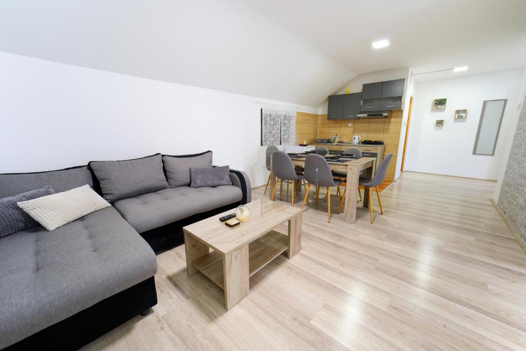 ein Wohnzimmer mit einem grauen Sofa und einem Tisch in der Unterkunft Studio Petra in Sokobanja