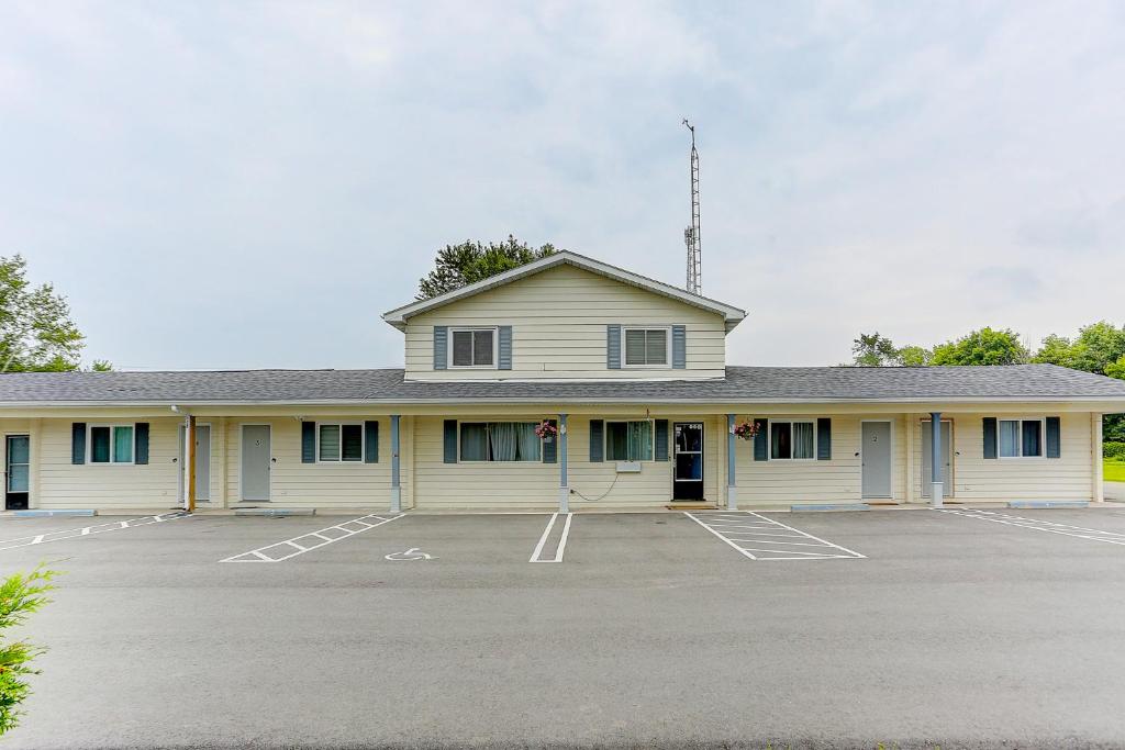 a large white building with a parking lot at Stone Fountain Motel in Fenelon Falls