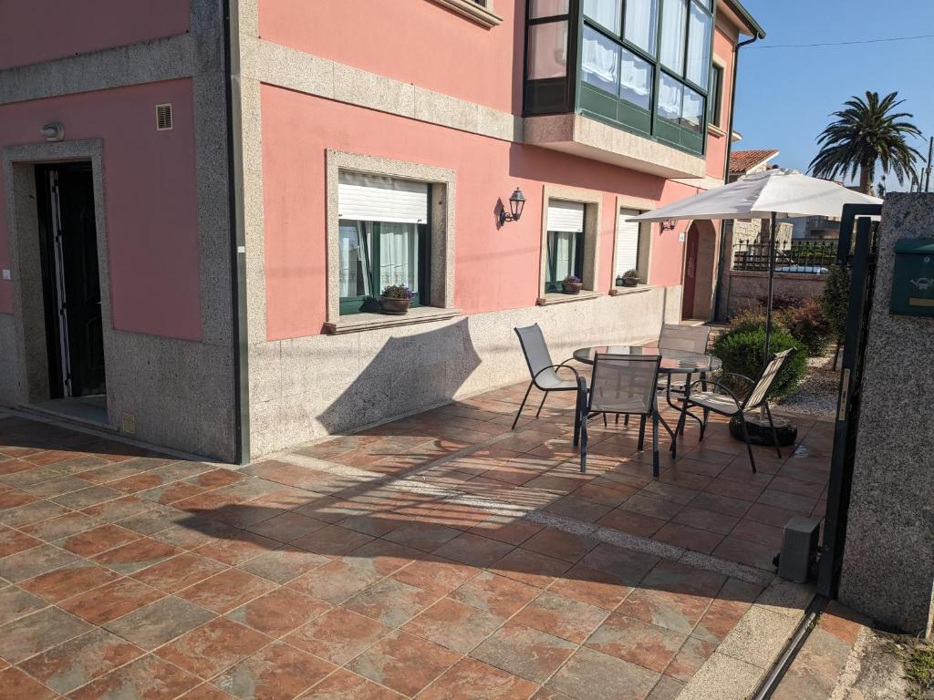 patio ze stołem, krzesłami i parasolem w obiekcie Alicia Bis w mieście Sanxenxo
