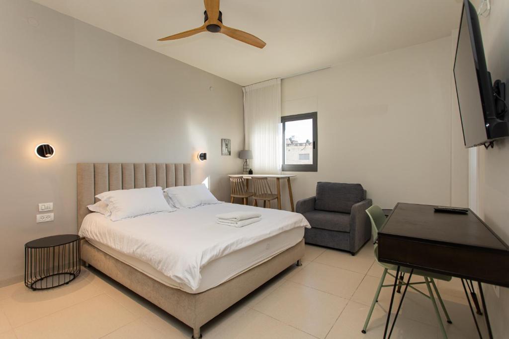 a bedroom with a bed and a chair and a television at Carmel Studio By Carmel Boutique in Haifa