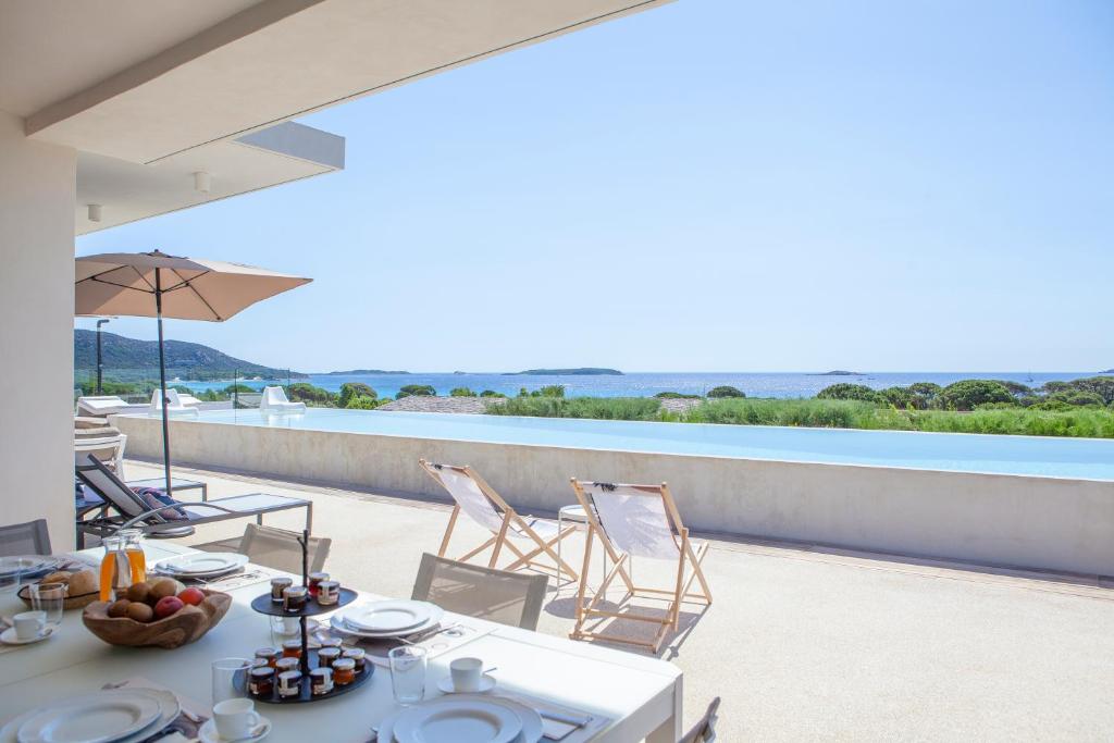 a table and chairs on a balcony with a view of the water at Villa Azai tu Suites in Porto-Vecchio