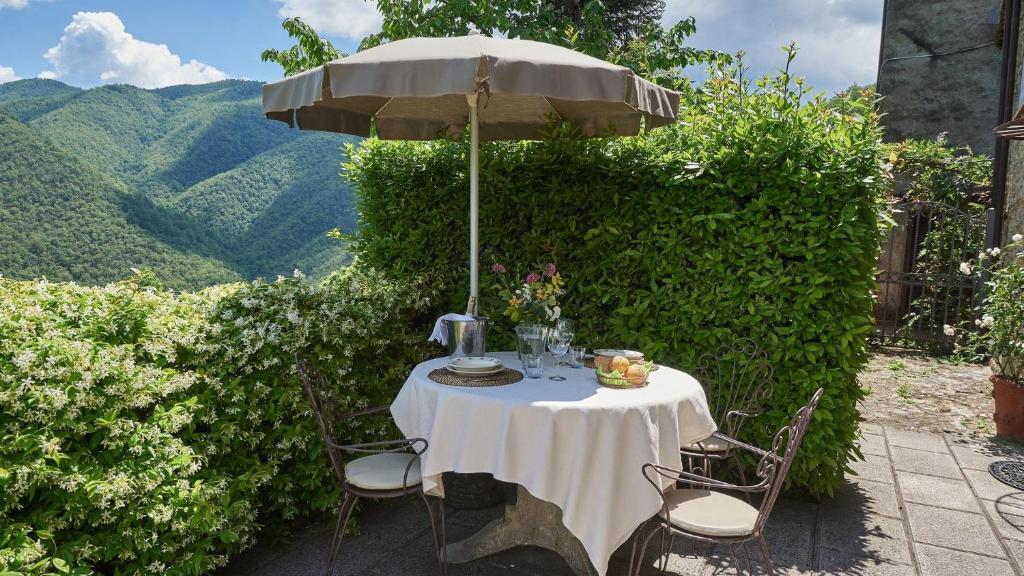 einen Tisch unter einem Sonnenschirm mit einem Tisch und Stühlen in der Unterkunft La Roccia in Bagni di Lucca