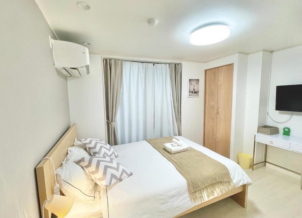 sypialnia z łóżkiem i telewizorem w obiekcie KOSUMOSU w Tokio