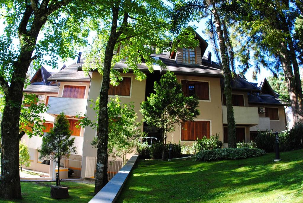 una casa con árboles delante de ella en Bavaria Residence - By Master Hotéis, en Gramado