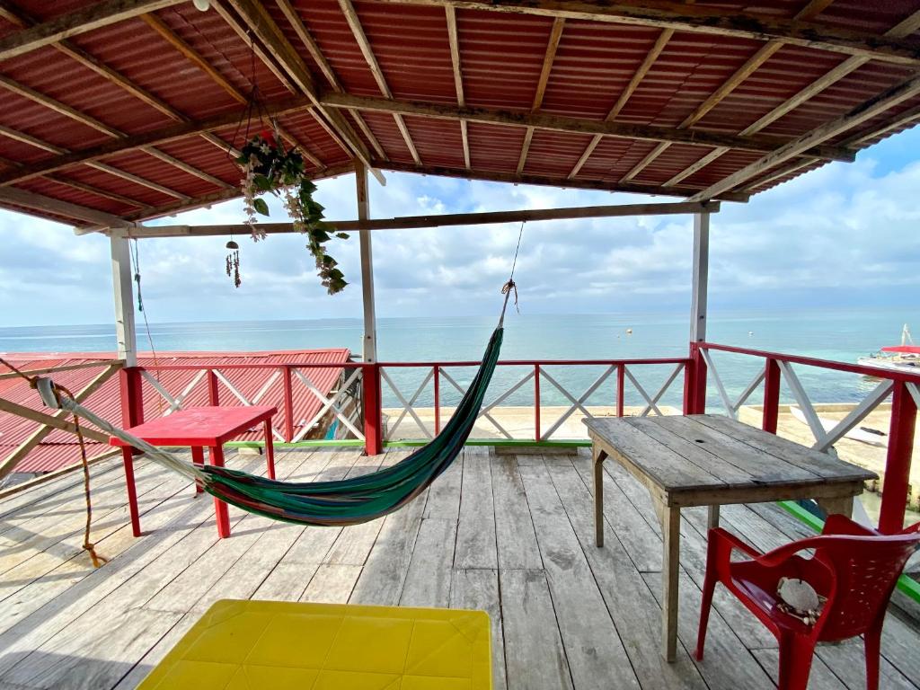 a hammock and a table on a deck with the ocean at Hostal Paraiso in Isla Mucura