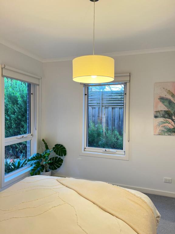 a bedroom with a bed and two windows at Rosebud Lovely House 2 - Mornington Peninsula 4 BR 3 Bath 2 story holiday house - BBQ - Beach - Hot spring in Rosebud