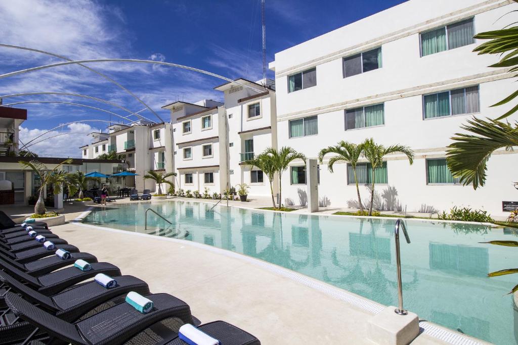 a swimming pool with lounge chairs in front of a building at Hotel Tulija Palenque in Palenque