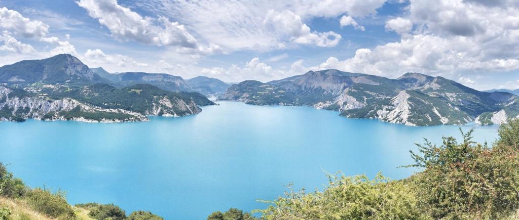 uma vista para um grande lago azul nas montanhas em Maison calme à proximité du Lac em Savines-le-Lac